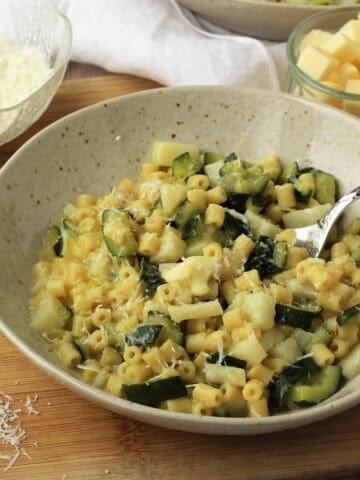 Creamy risotto pasta with zucchini spooned from bowl.