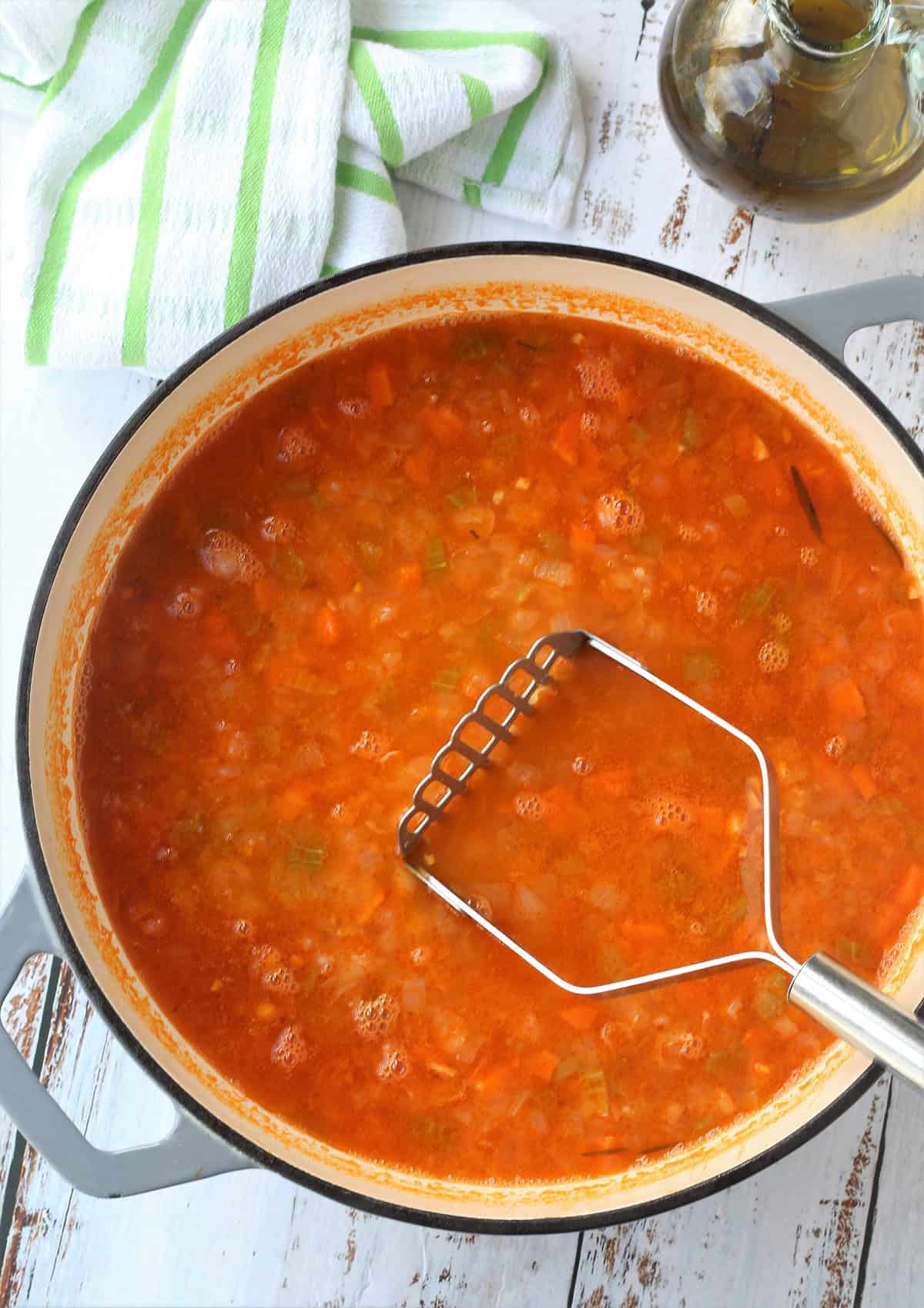 Chickpeas in tomato sauce mashed with potato masher.