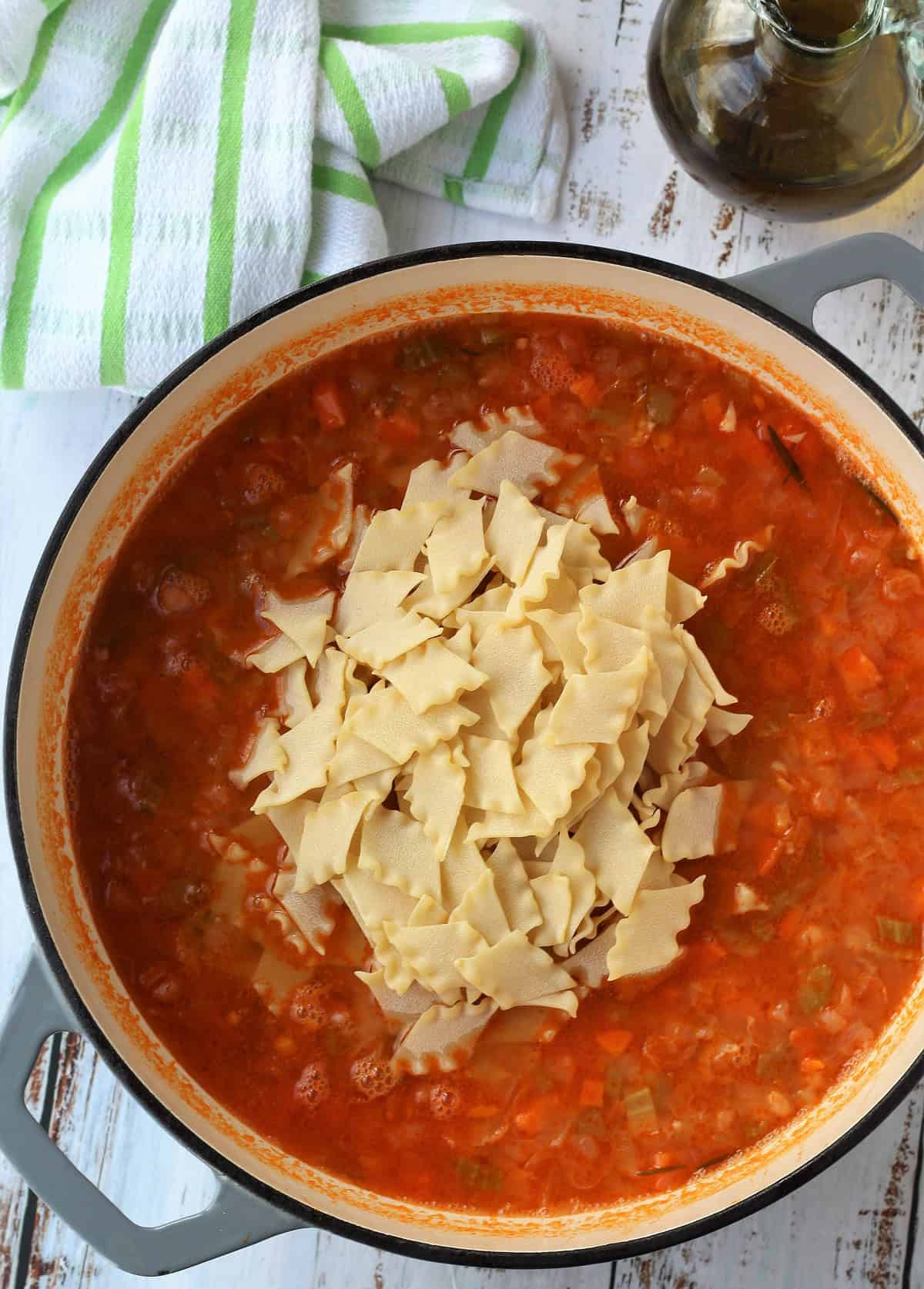 Pasta added to chickpea tomato sauce in skillet.
