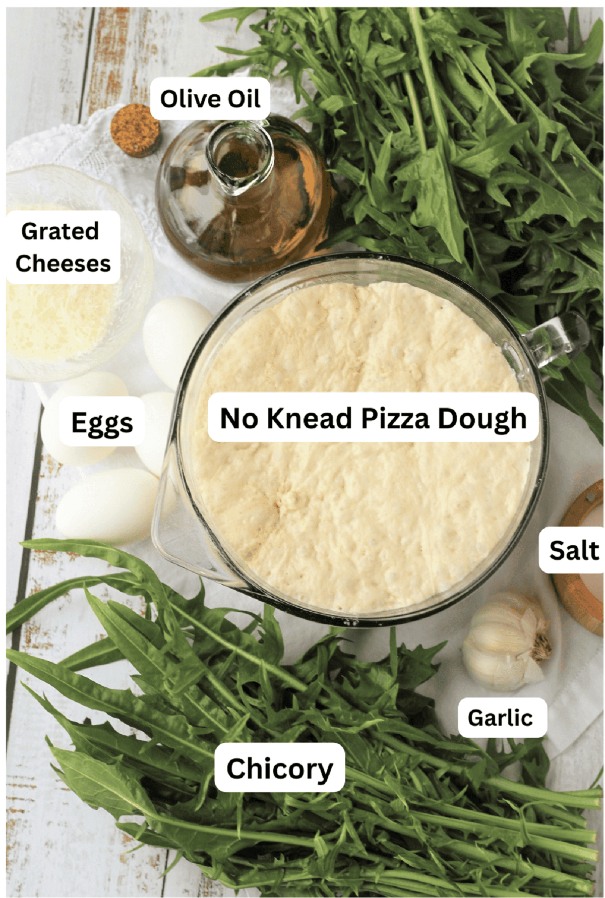 Chicory leaves, pizza dough, salt, garlic, eggs, grated cheese and olive oil bottle.