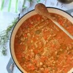 Creamy chickpeas with pasta in large pan with wooden spoon.