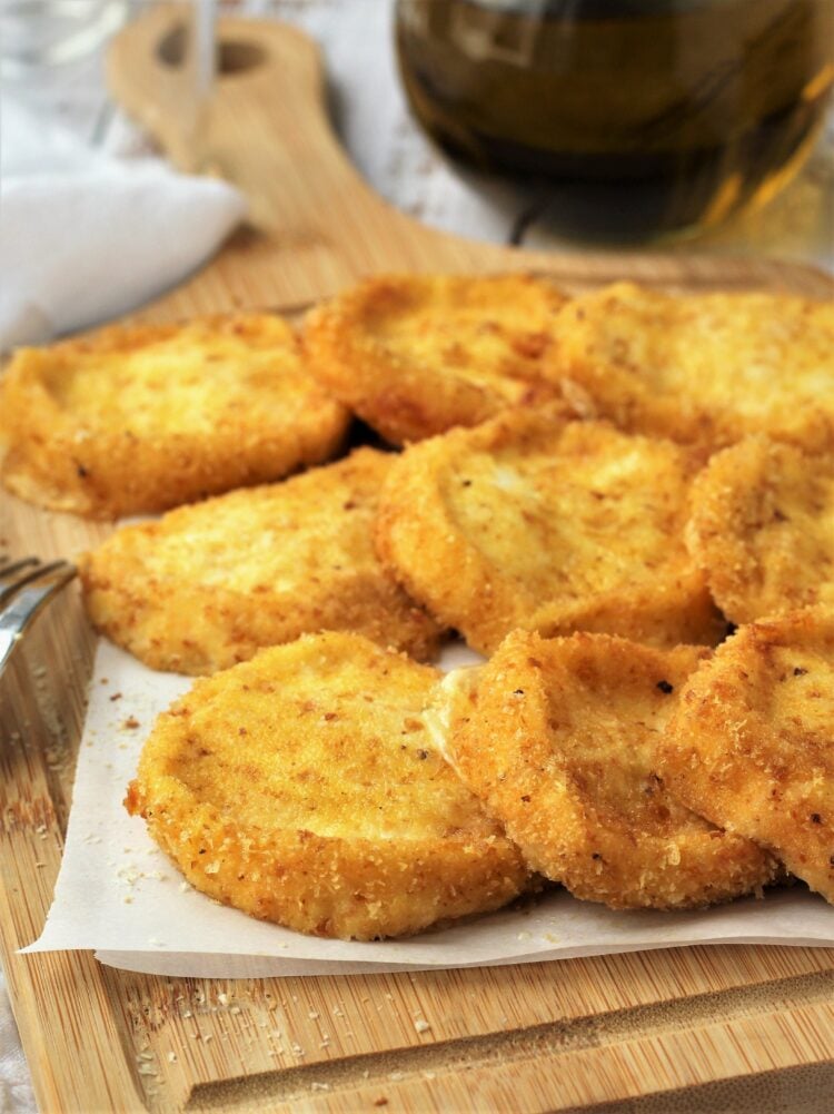 Breaded tuma cheese pieces on wood board.