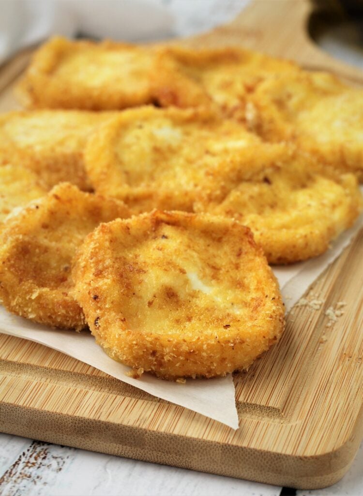 Breaded fried tuma cheese on wood board.