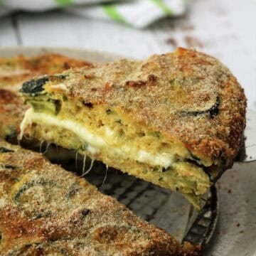 Baked cheesy zucchini frittata wedge served on spatula.