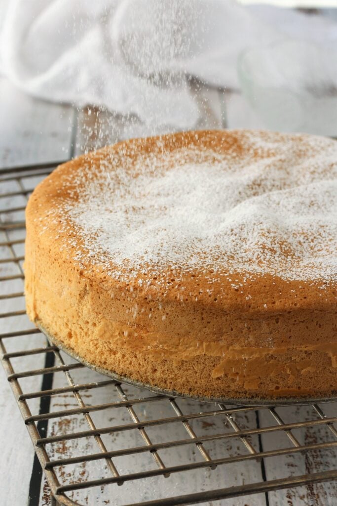 Pan di spagna on wire rack dusted with powdered sugar.