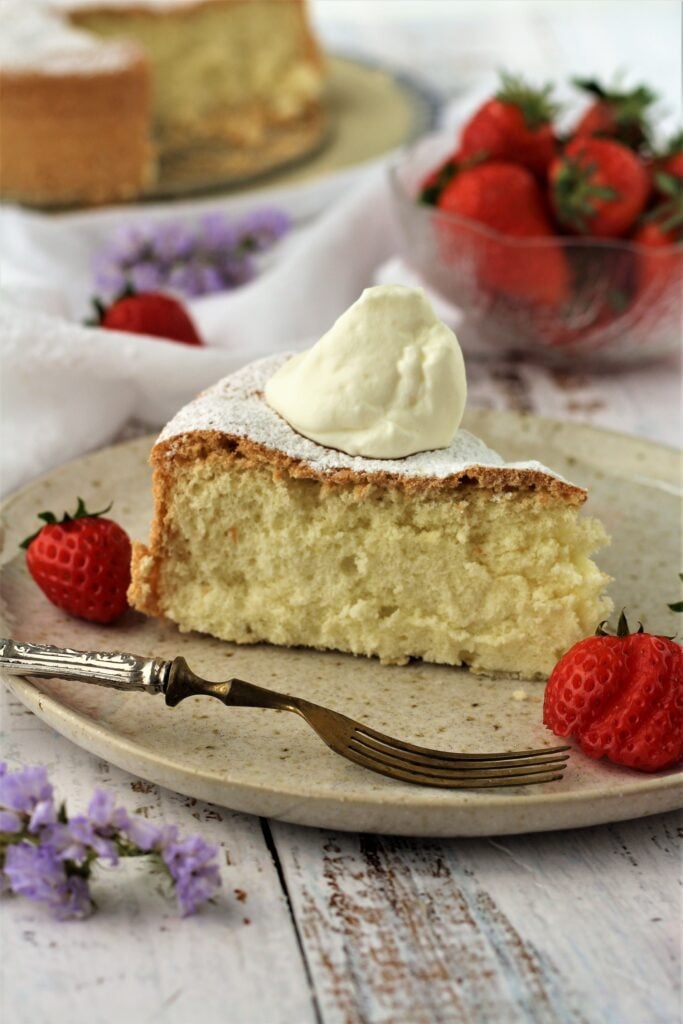 Slice of sponge cake with whipped cream and strawberries.