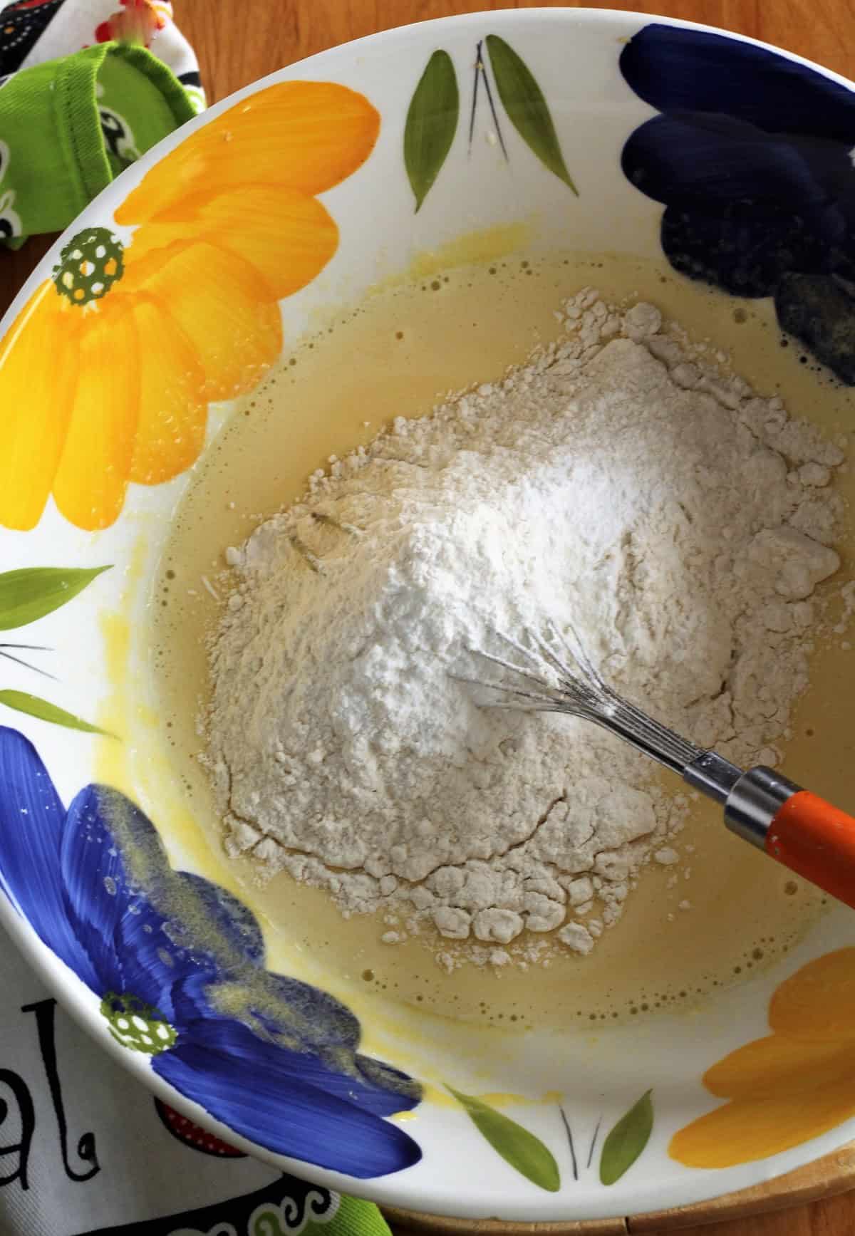 Flour whisked into wet ingredients for hazelnut cake.
