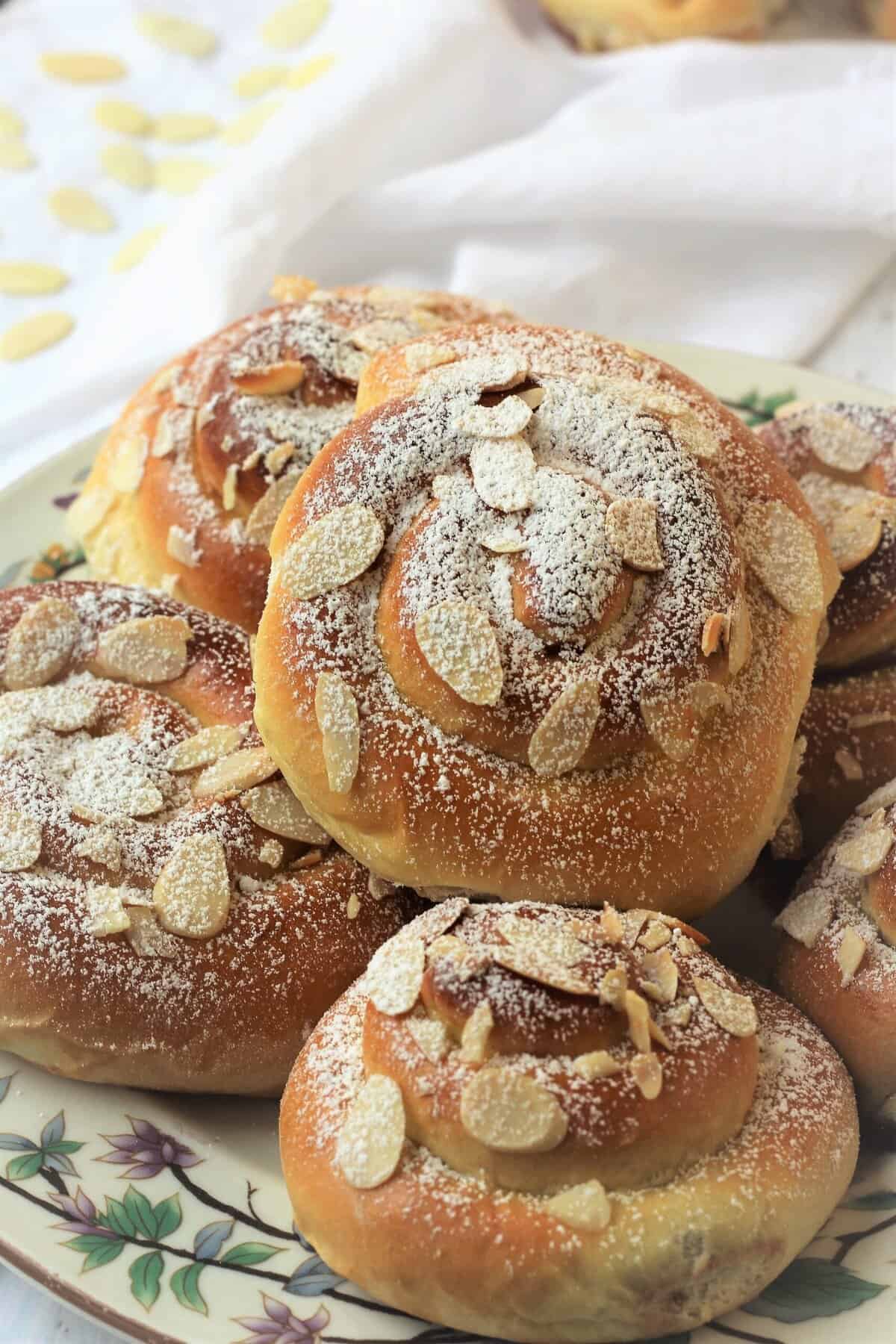Brioche swirls filled with jam and topped with almonds on plate.