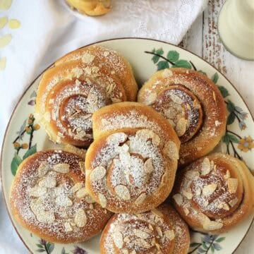 Brioche swirls with jam and topped with almonds on plate with one cut in half next to plate.