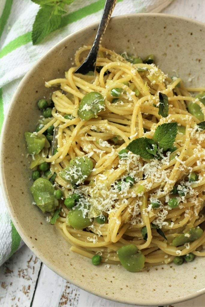 Bowl of spaghetti with fava beans, peas and mint.