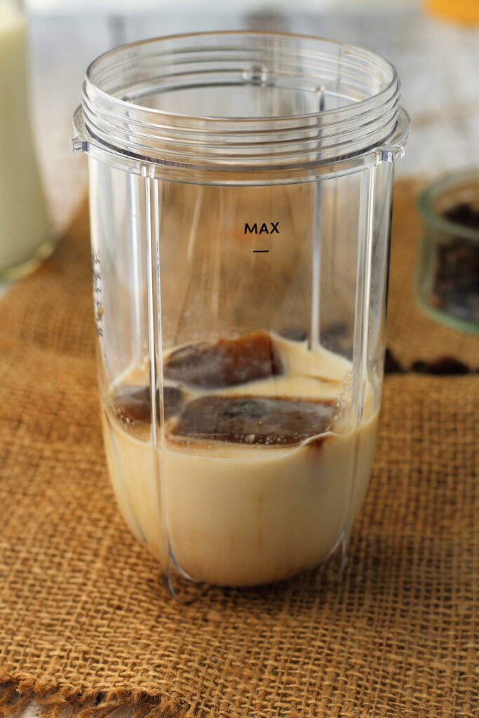Frozen coffee cubes and milk in blender glass.