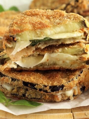 Melanzane in carrozza (fried and breaded eggplant and cheese sandwich), cut open on wood board.
