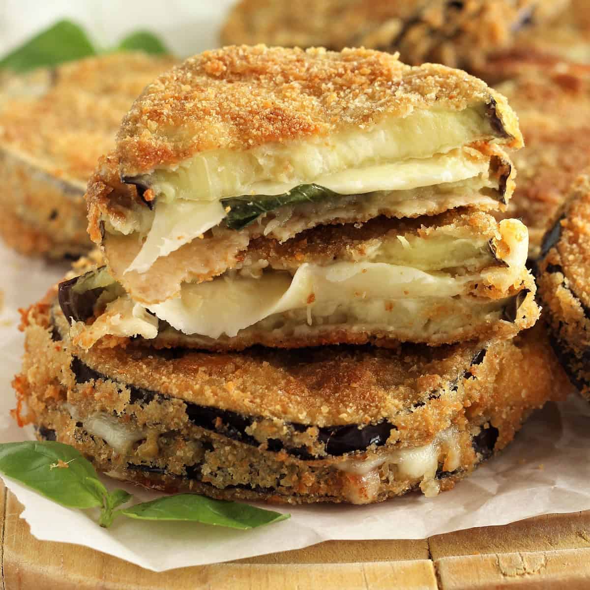 Melanzane in carrozza (fried and breaded eggplant and cheese sandwich), cut open on wood board.