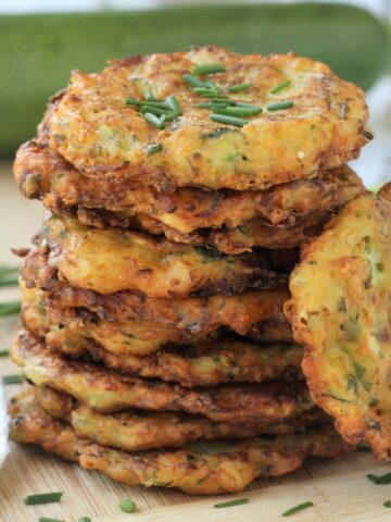 Piled Italian zucchini fritters topped with chives.