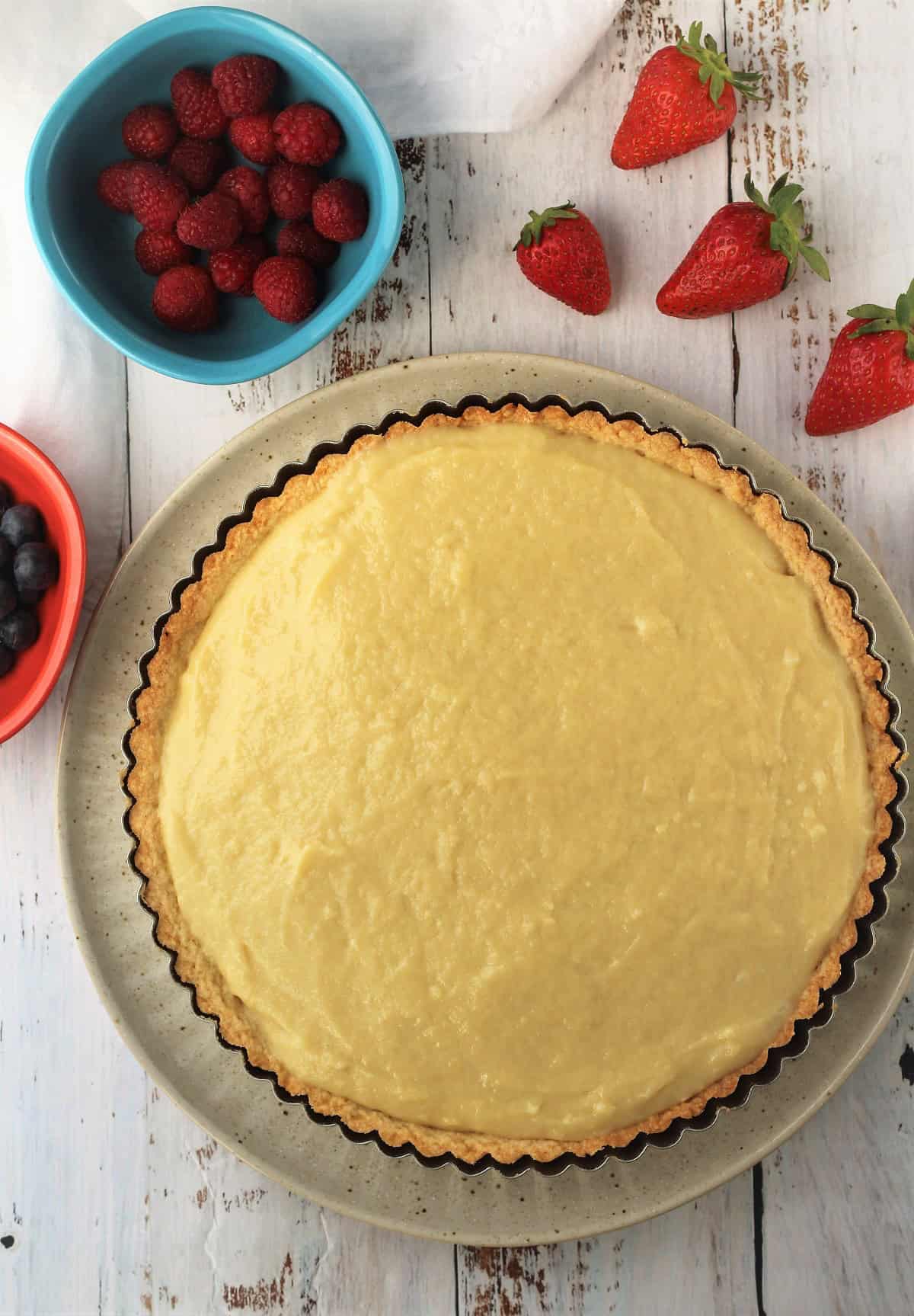 Pastry shell filled with pastry cream surrounded by cut fruit for fruit tart.