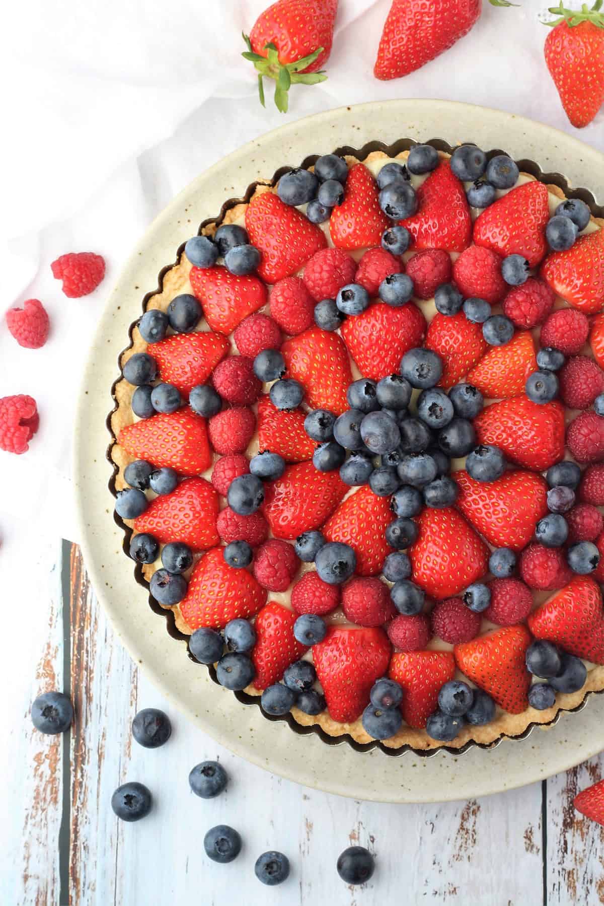 Pastry cream filled tart shell topped with cut berries.