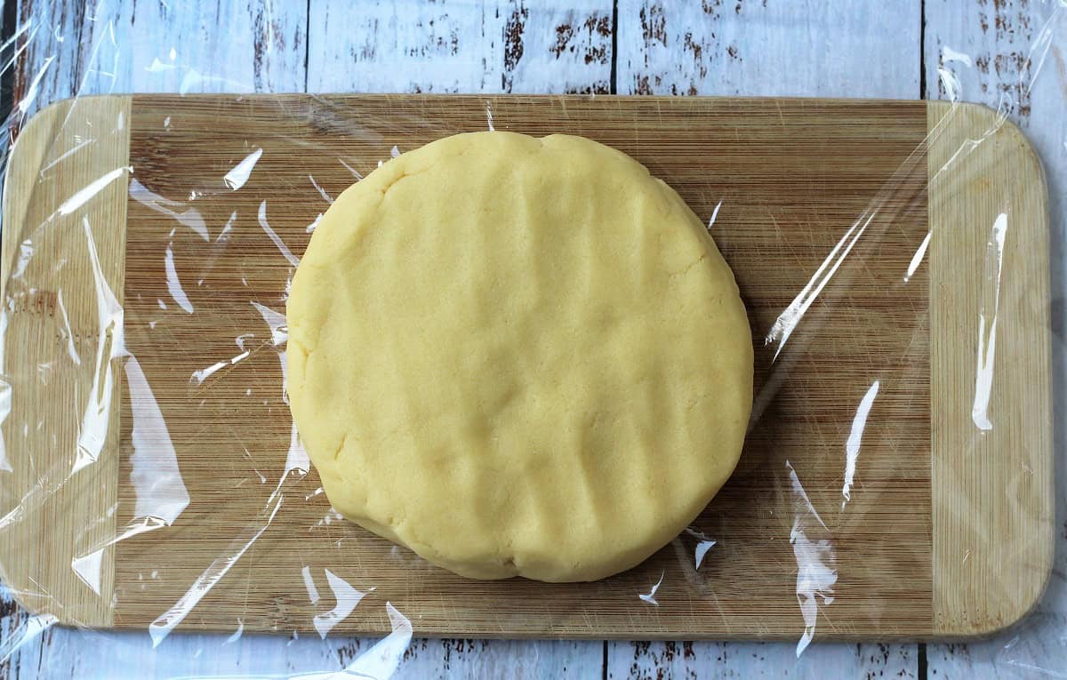 Pastry dough shaped into disc on plastic wrap.