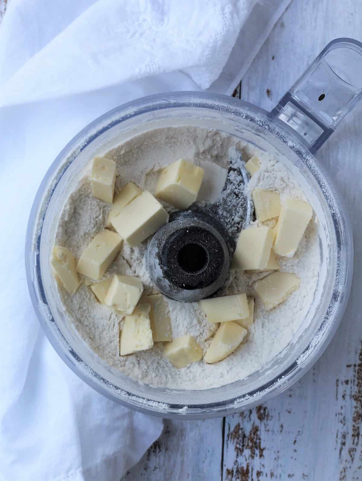 Cubed butter added to flour in food processor bowl for pastry dough.