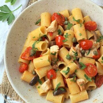 Bowl of pasta with swordfish, cherry tomatoes, capers and olives.