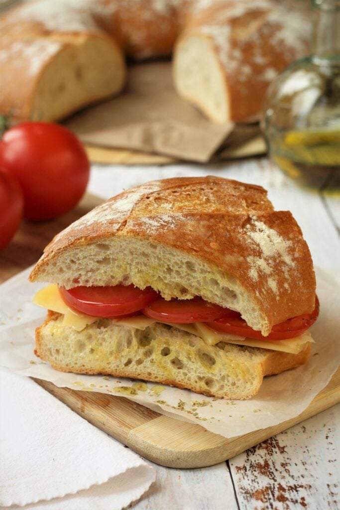 Pane cunzatu, Sicilian sandwich, with tomatoes and cheese on wood board.