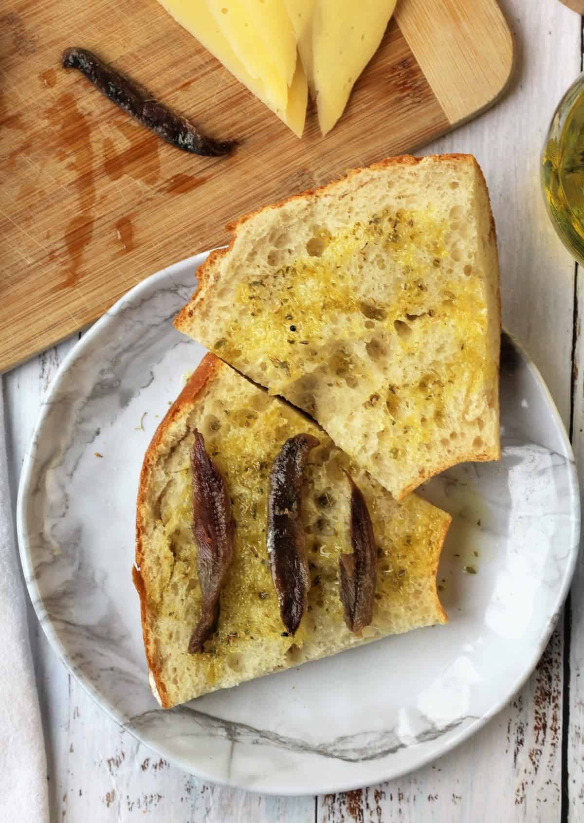 Bread for pane cunzatu topped with olive oil, oregano and anchovies.