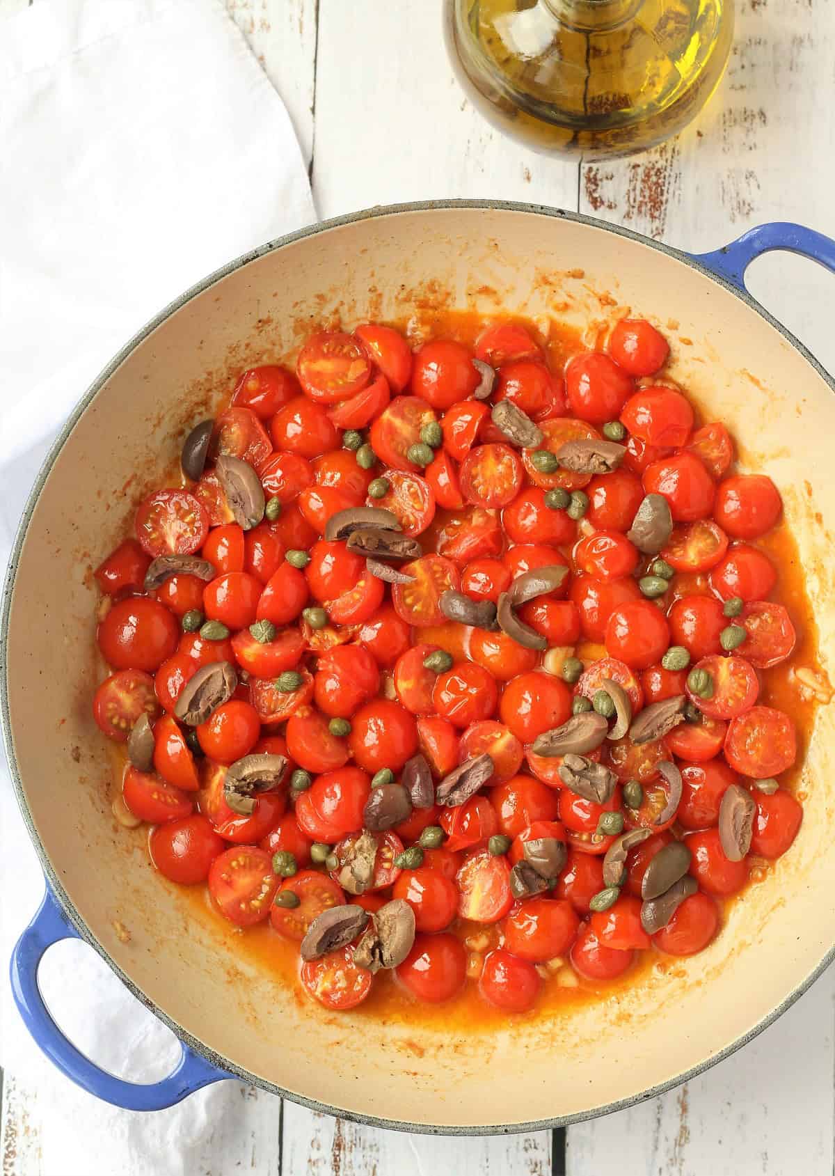 Cherry tomato sauce with capers and olives in large skillet.