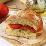 Pane cunzatu- Sicilian sandwich on wood board with tomato, olive oil and oregano.