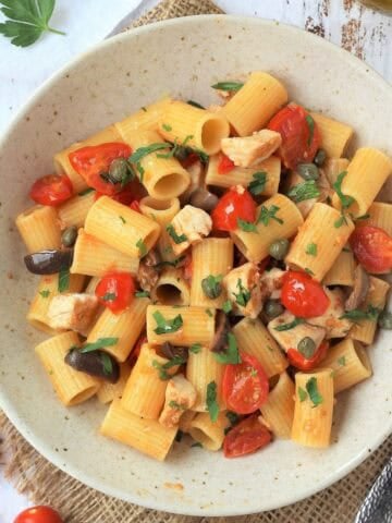 Swordfish pasta with cherry tomato, olive and caper sauce in bowl.