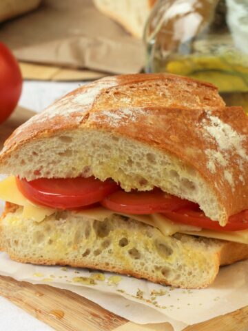 Wedge of Sicilian sandwich with tomatoes, cheese, olive oil and oregano.