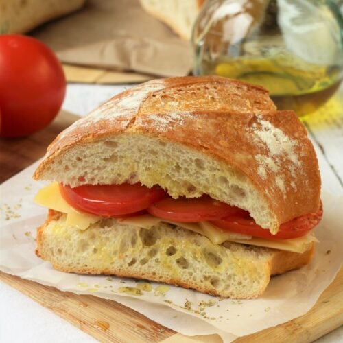Wedge of Sicilian sandwich with tomatoes, cheese, olive oil and oregano.