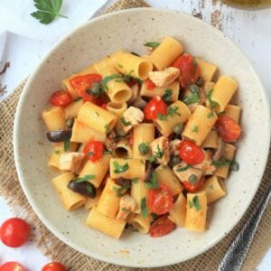 Plate of pasta with swordfish, cherry tomatoes, capers and olives.