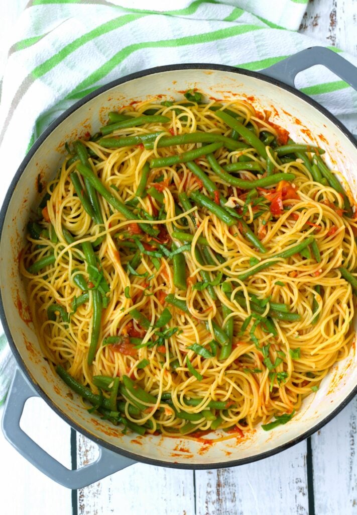 Spaghetti with green beans in tomato sauce in large skillet.