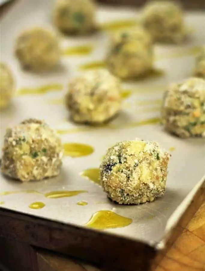 Eggplant meatballs on baking sheet drizzled with oil.