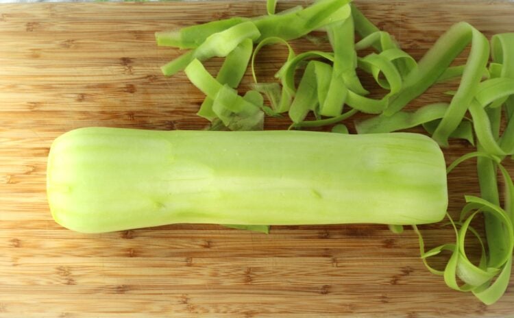 Peeled cucuzza longa on wood board.