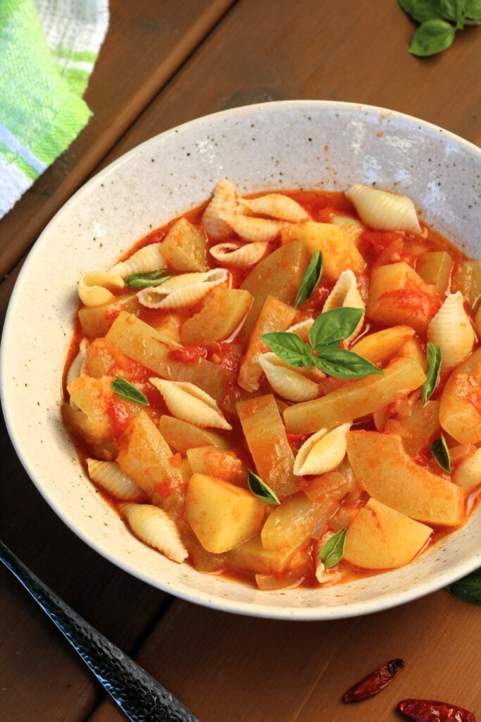 Cucuzza with tomatoes, potatoes and pasta in bowl with basil.