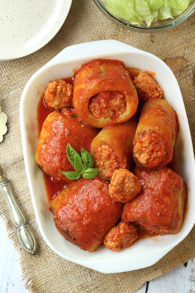 Cucuzza squash stuffed with meatball in tomato sauce in rectangular dish.
