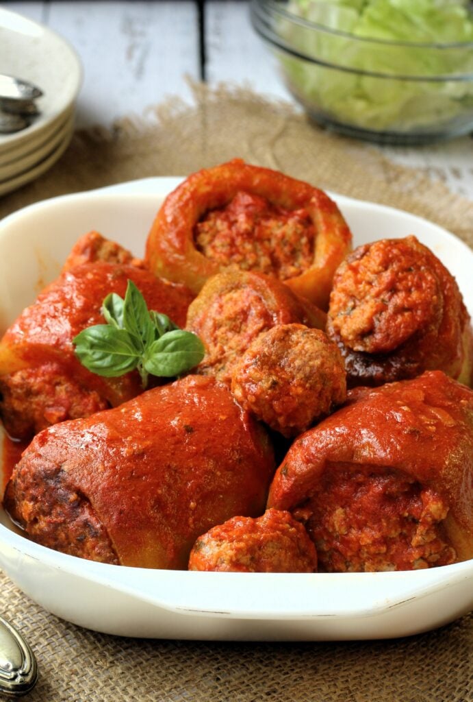 Cucuzza squash filled with meatball stuffing in tomato sauce in white dish.