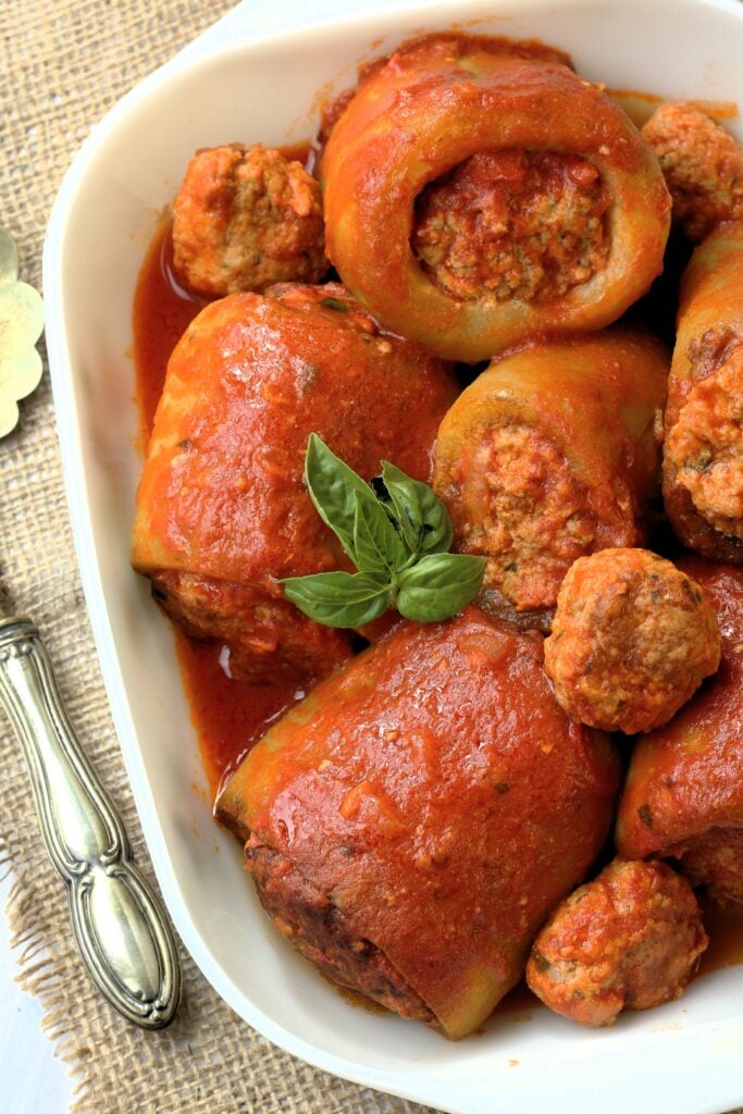 Stuffed Sicilian cucuzza with meatball filling in tomato sauce in rectangular dish.