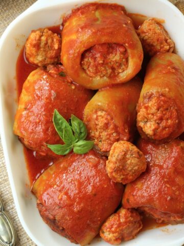 Stuffed cucuzza pieces in tomato sauce in rectangular serving dish.