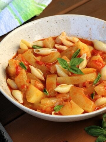Sicilian cucuzza with tomatoes, potatoes and pasta in bowl with basil.