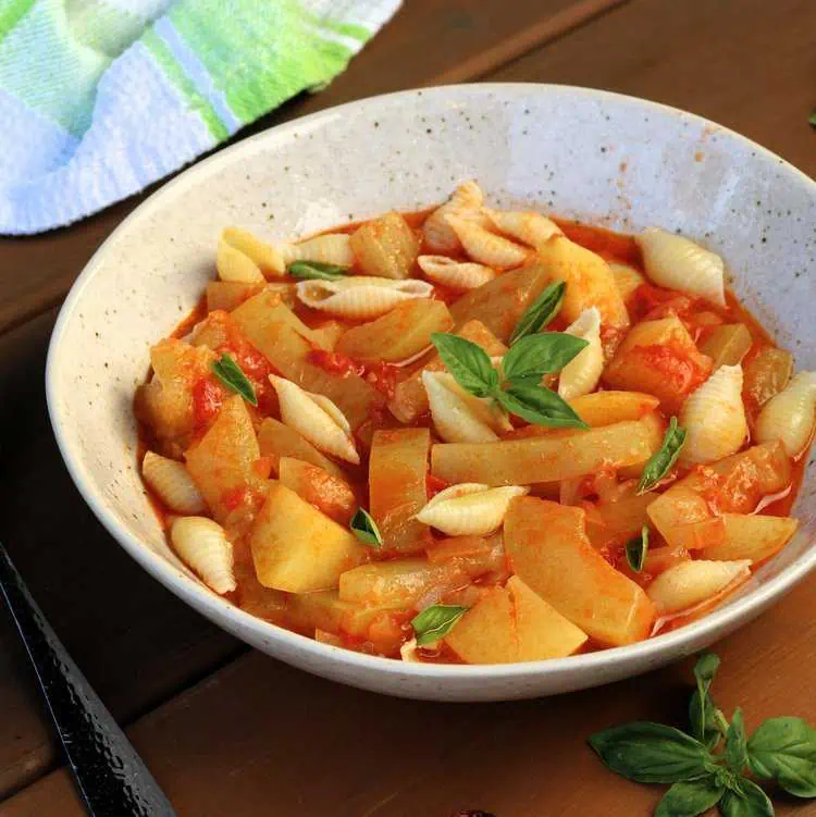 Sicilian cucuzza with tomatoes, potatoes and pasta in bowl with basil.