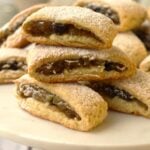 Cuccidati cookies with cucuzzata on white round plate.