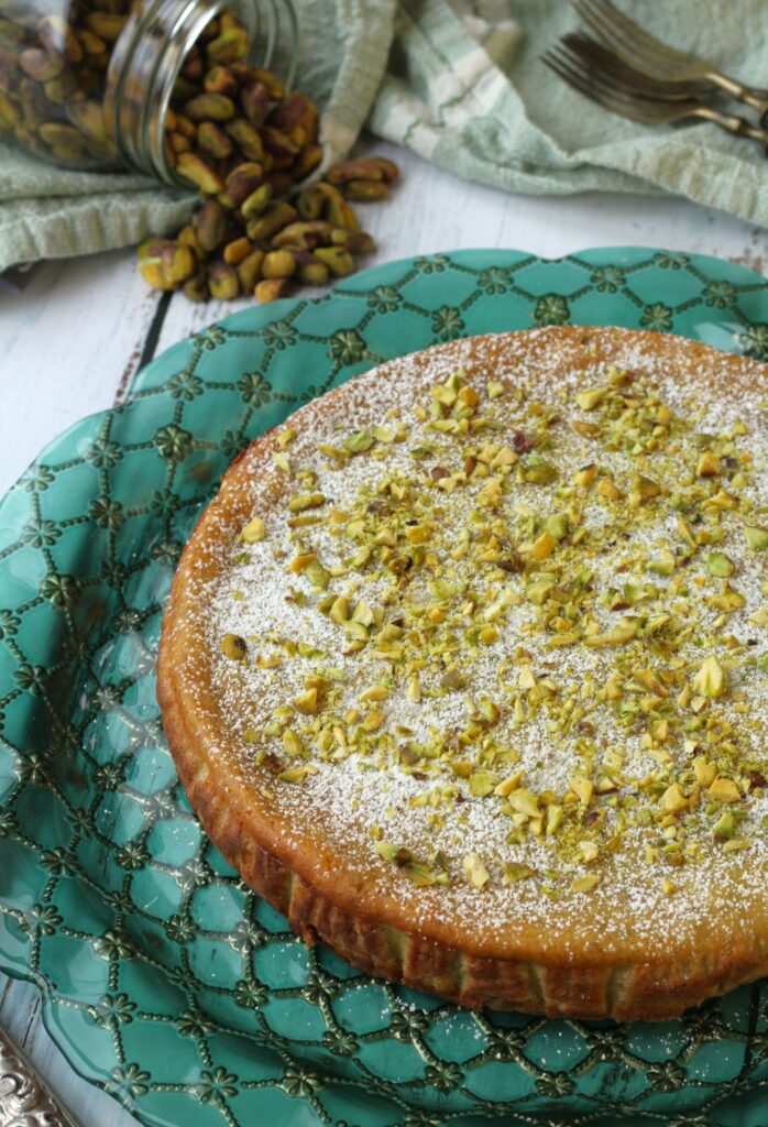 No crust ricotta pistachio cheesecake on green round plate.