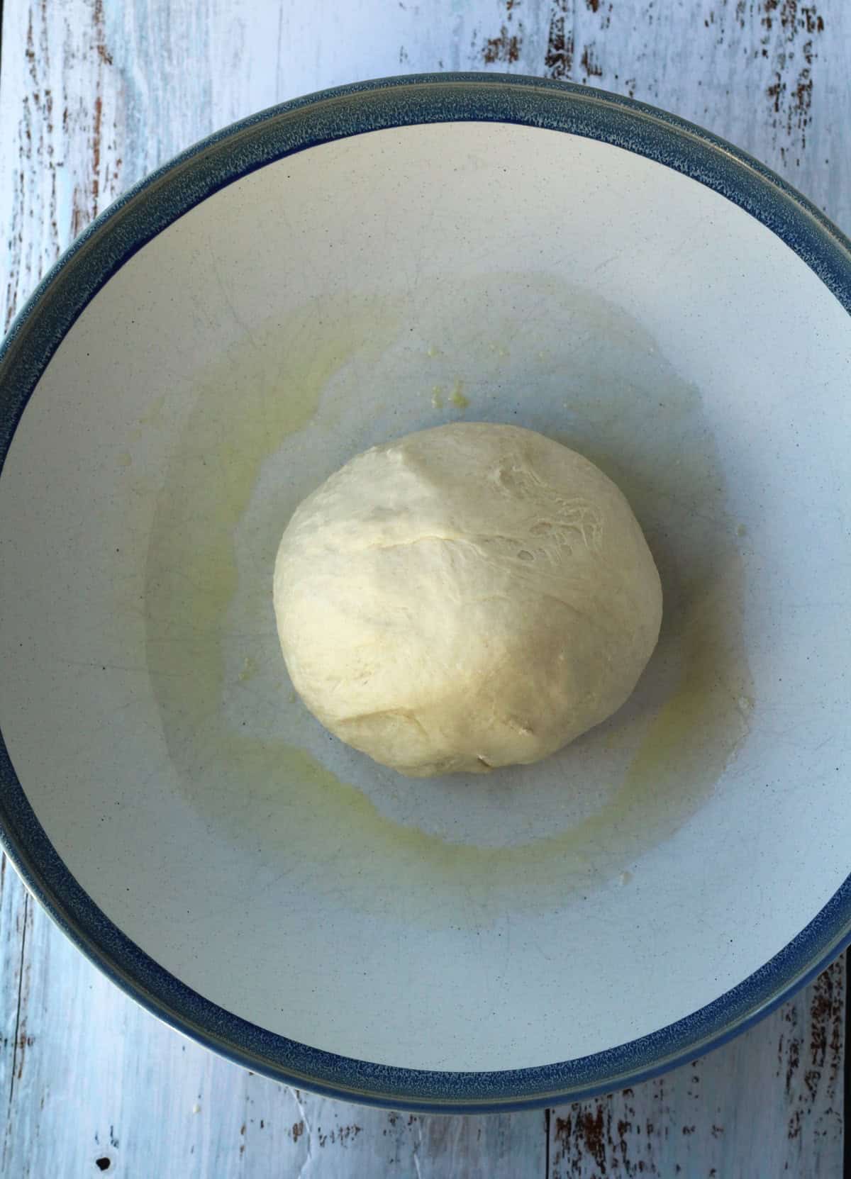 Brioche dough shaped into a ball in large bowl.