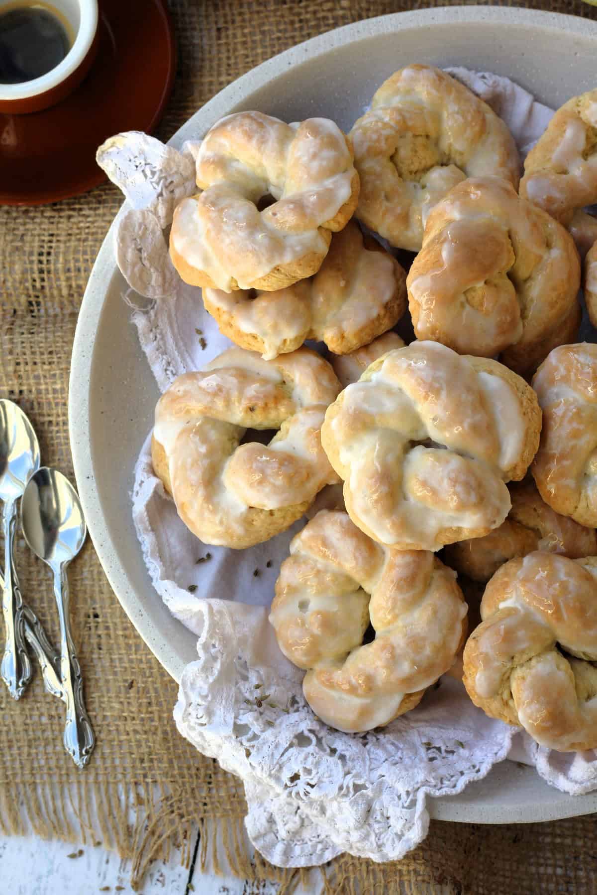 Sicilian anise lemon taralli cookies coated in glaze piled on plate.
