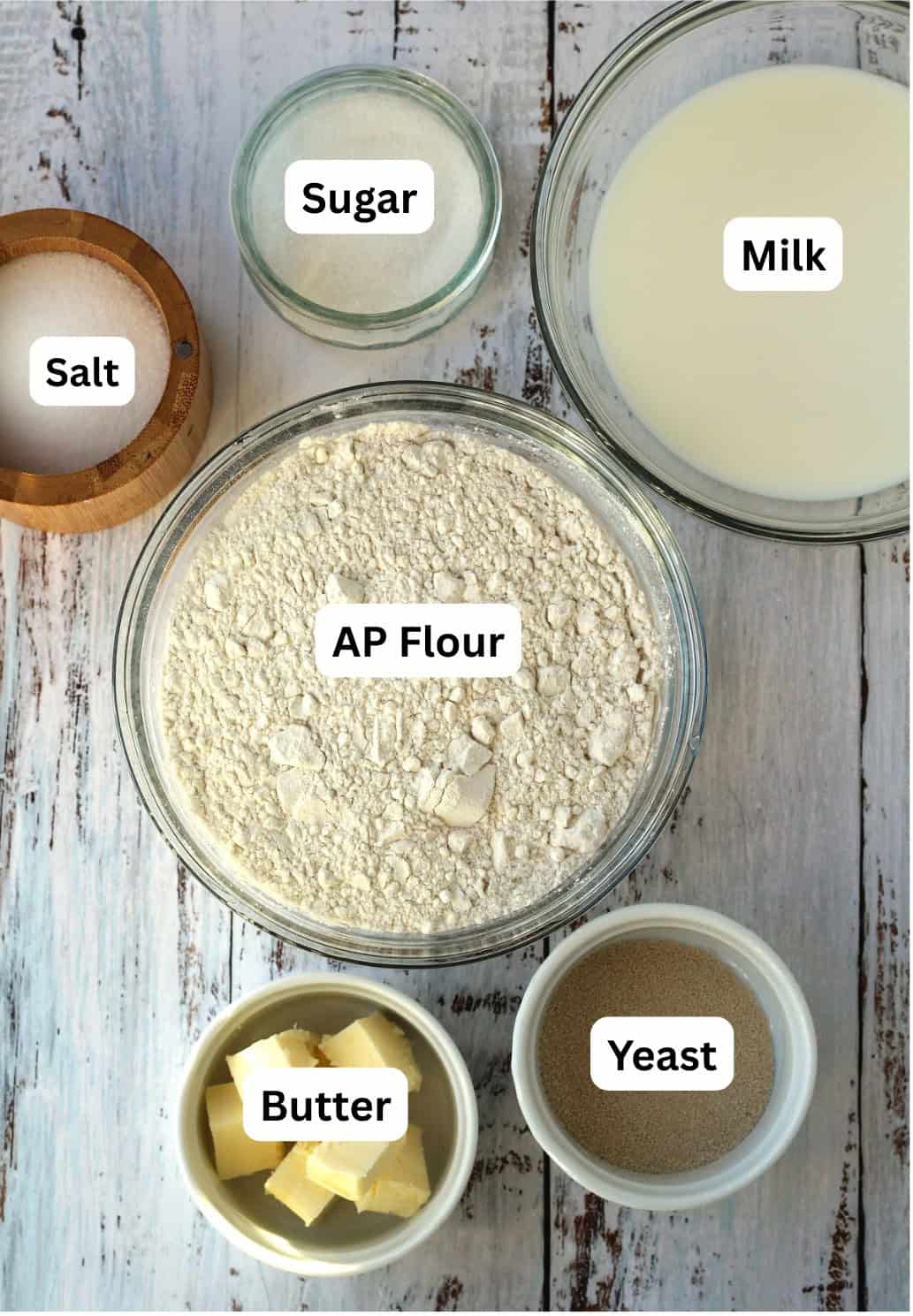 Bowls of flour, milk, yeast, butter, salt and sugar.