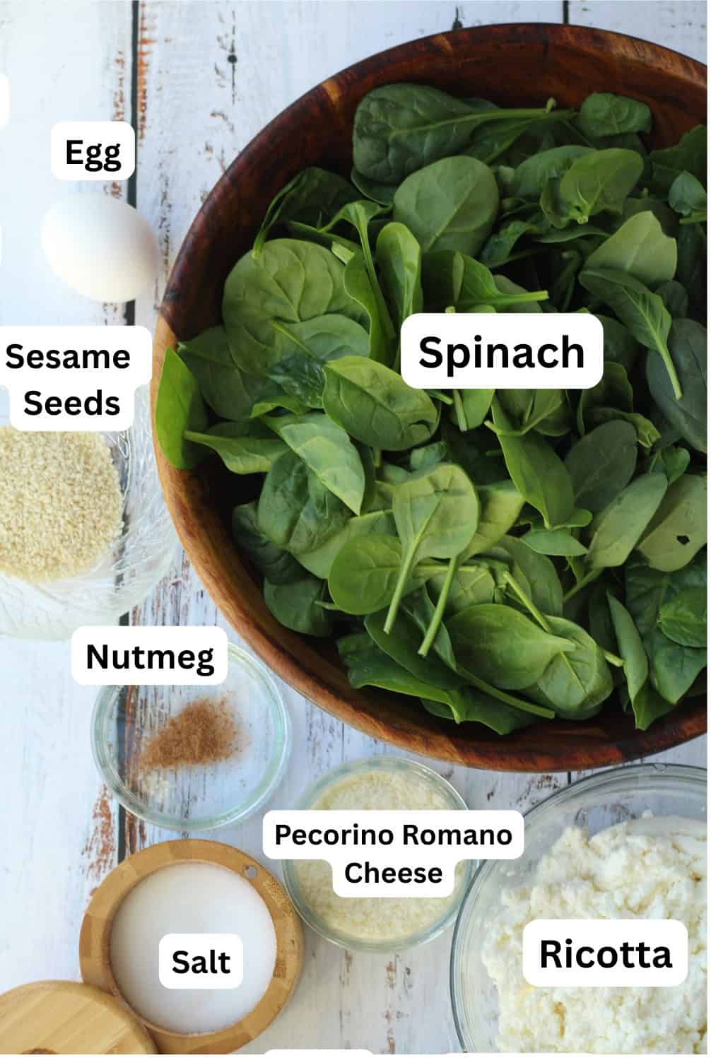Bowls with spinach, ricotta, grated cheese, salt, numeg, sesame seeds and an egg.