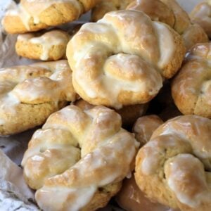 Sicilian anise lemon taralli cookies with lemon glaze piled on plate.