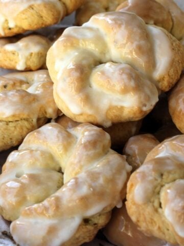 Sicilian anise lemon taralli cookies with lemon glaze piled on plate.