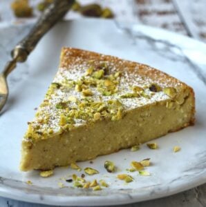 Slice of ricotta pistachio cheesecake on plate with fork.